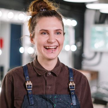 Peluquera sonriendo con delantal de trabajo en el salón